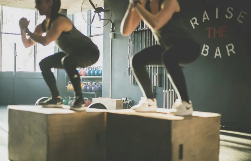 Duas alunas saltando sobre caixas de treino