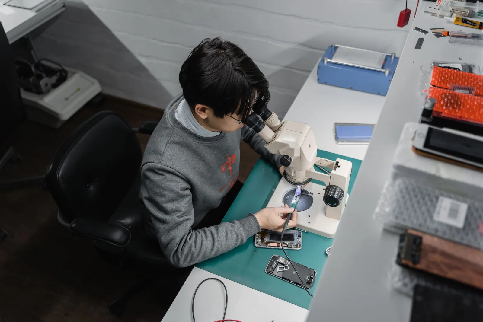 Técnico usando microscópio na bancada de reparo