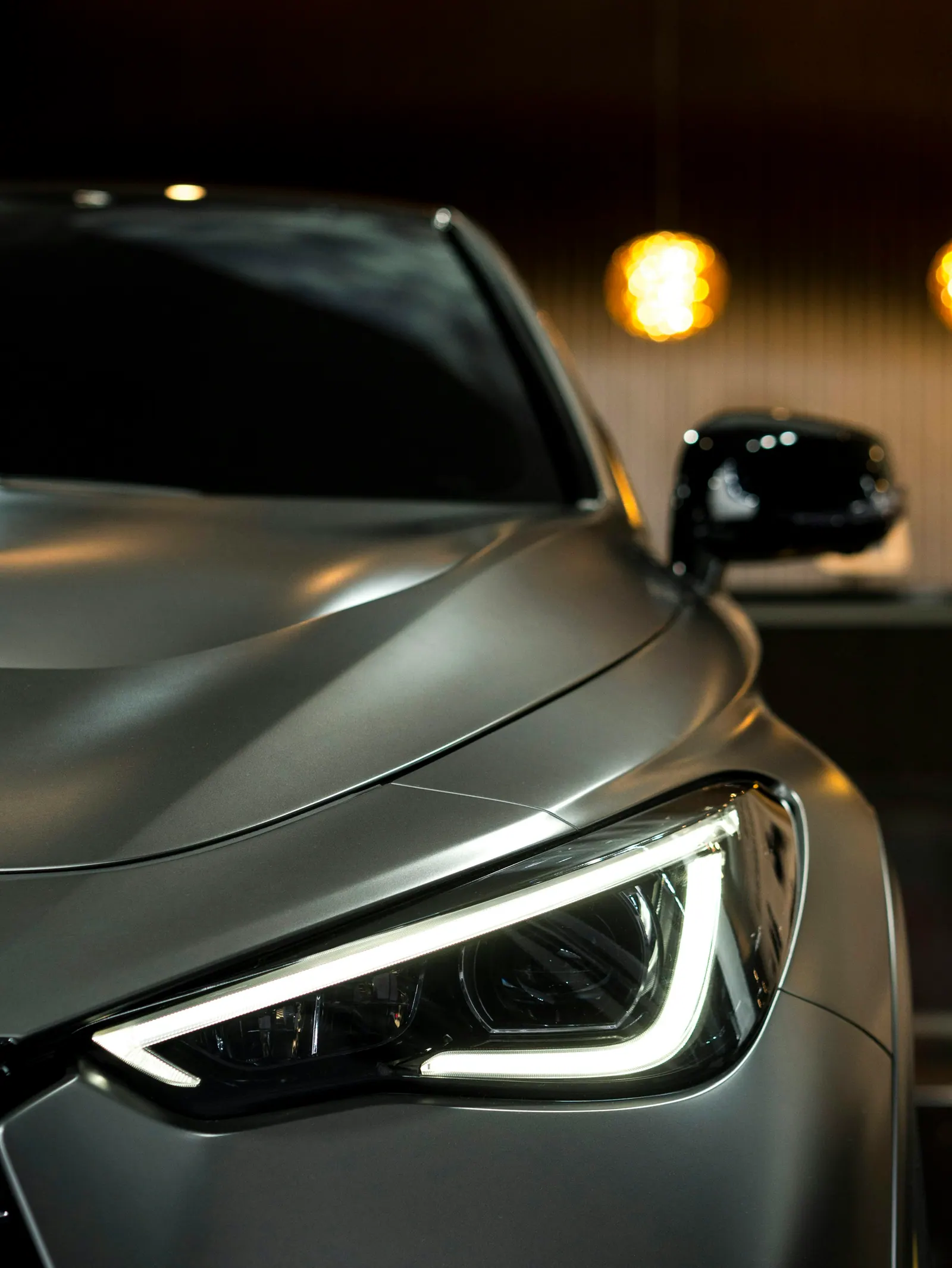 Farol de carro prata em garagem com luzes quentes