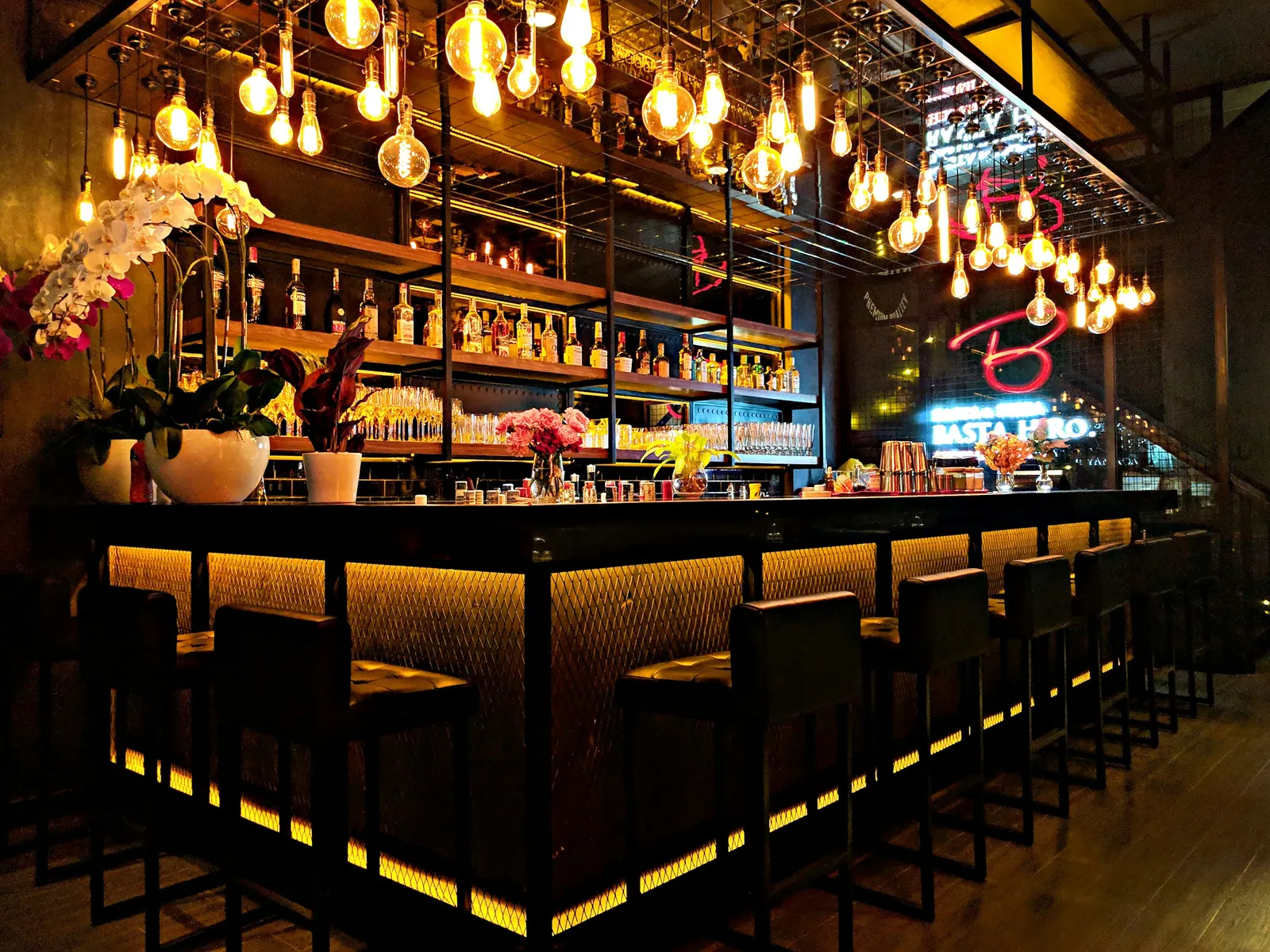 Balcão do bar iluminado por lâmpadas penduradas e prateleiras de garrafas