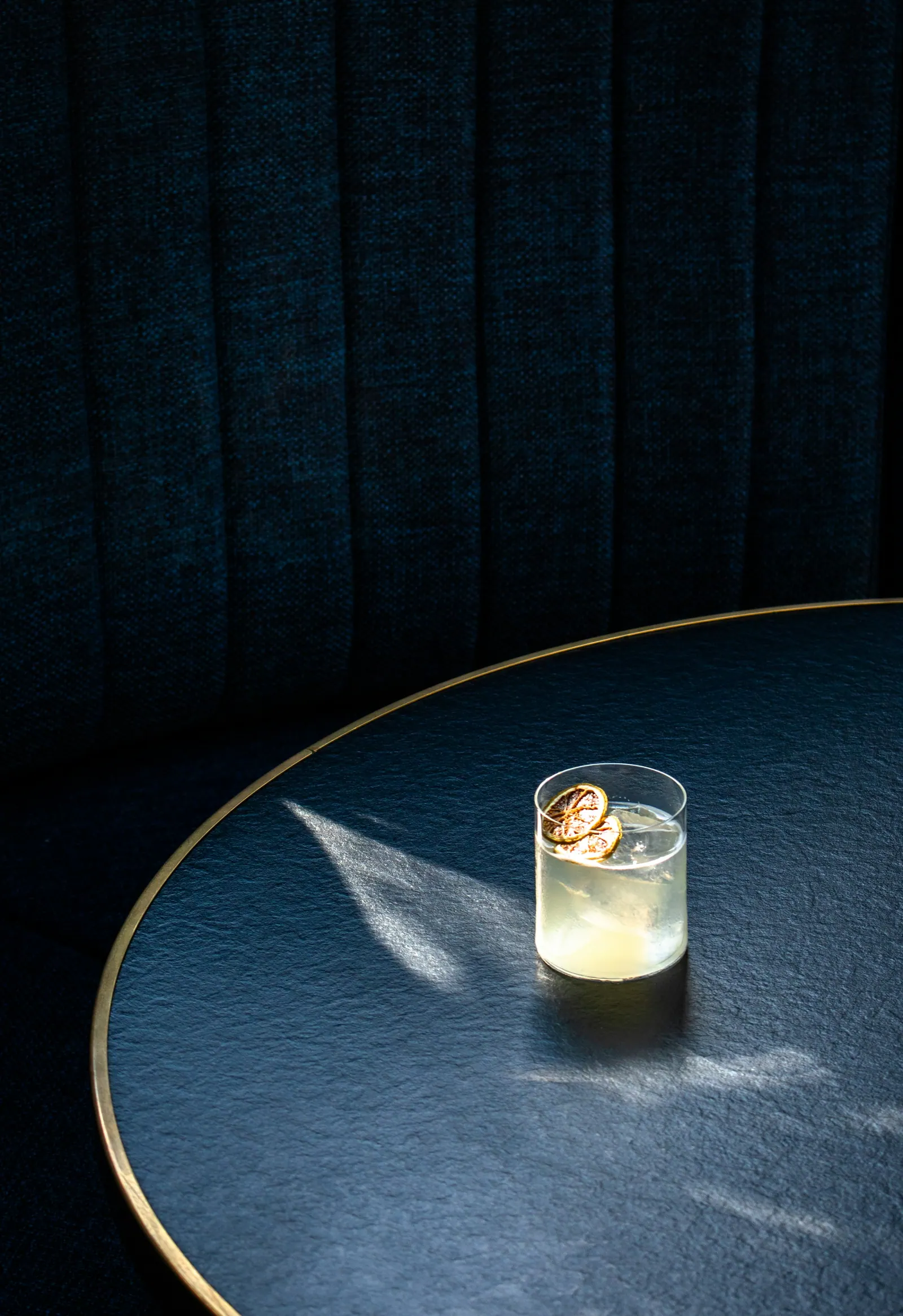 Copo de drink com gelo sob luz dramática na mesa escura