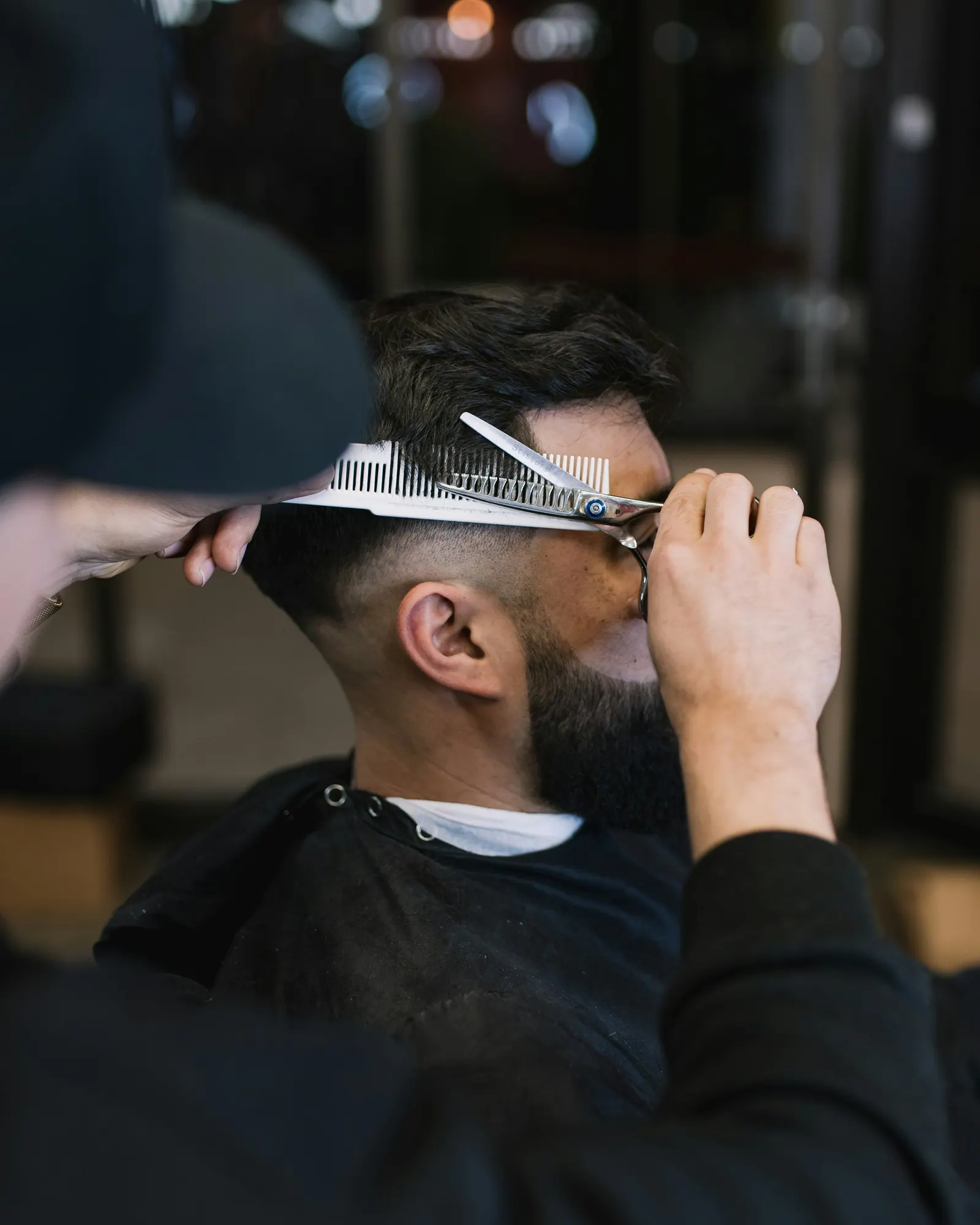 Barbeiro cortando cabelo com tesoura e pente
