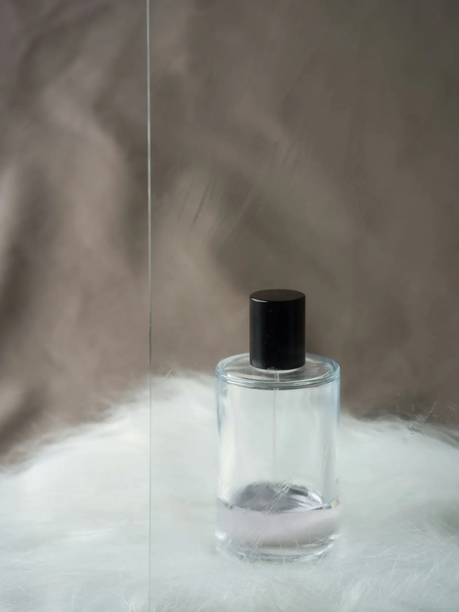 Frasco de perfume transparente sem marca sobre pelúcia branca