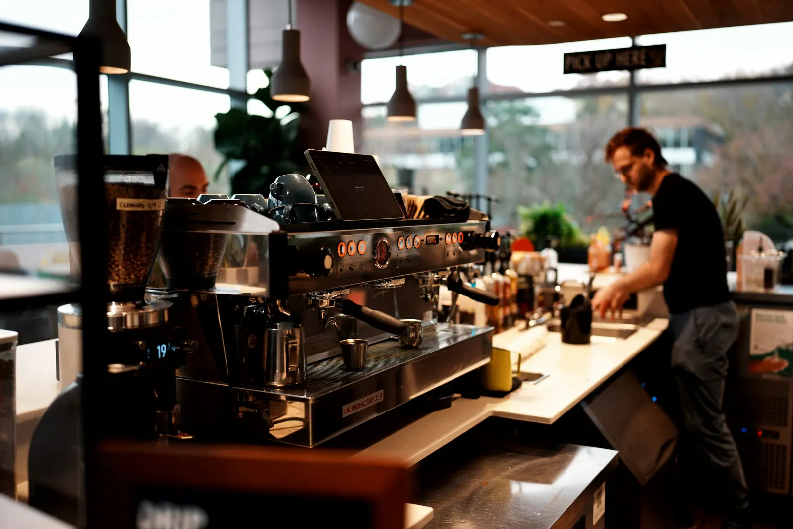Balcão de cafeteria com máquina de espresso e barista