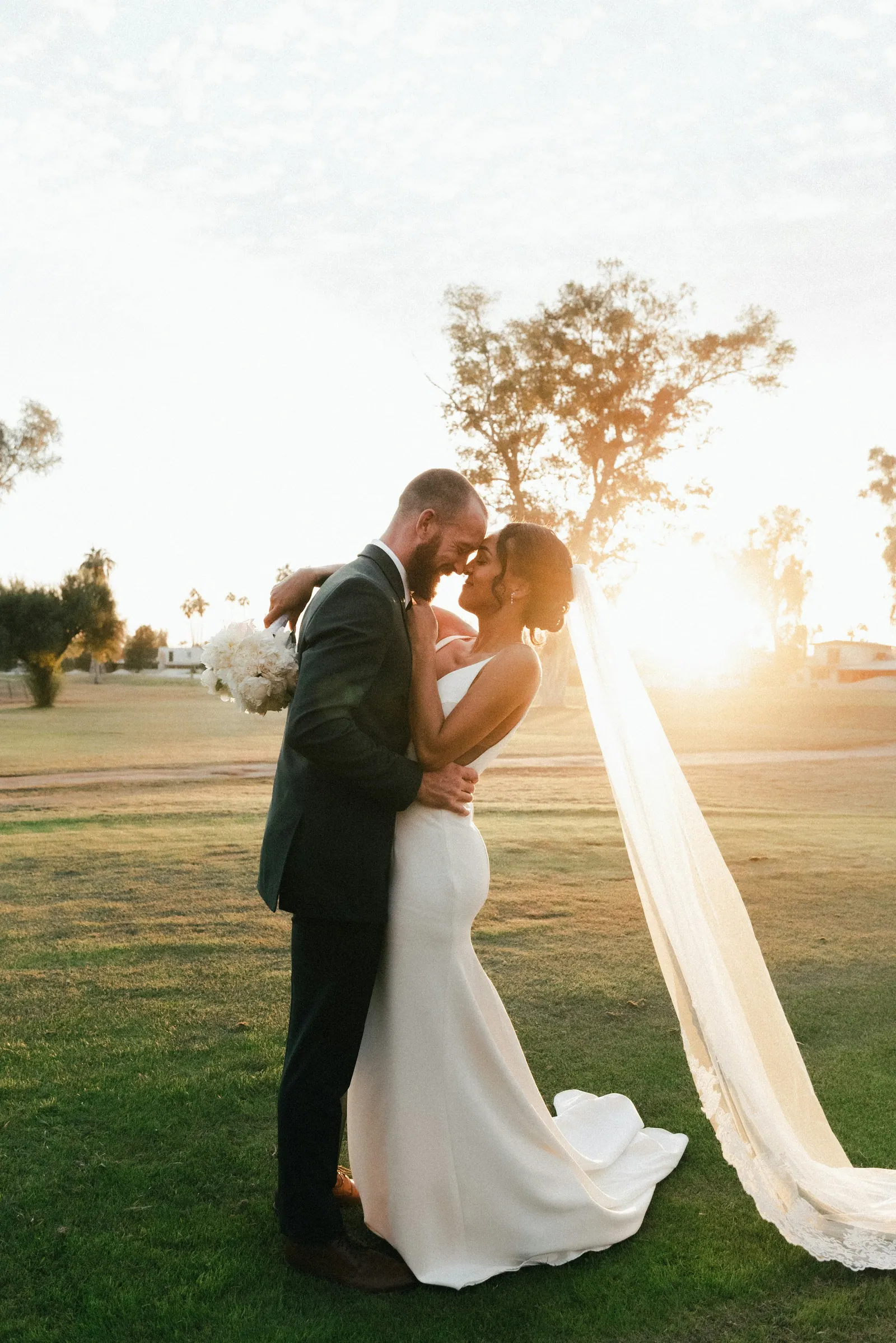 Casal de noivos se beijando ao pôr do sol