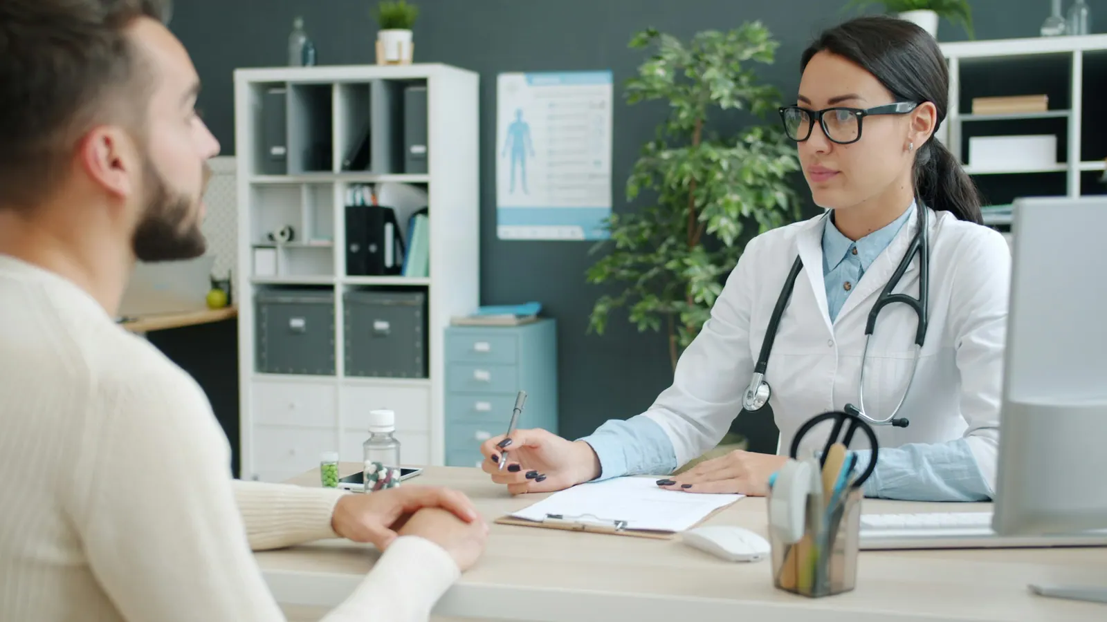 Médica conversando com um paciente na mesa do consultório