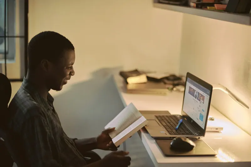 Estudante lendo à noite ao lado do notebook