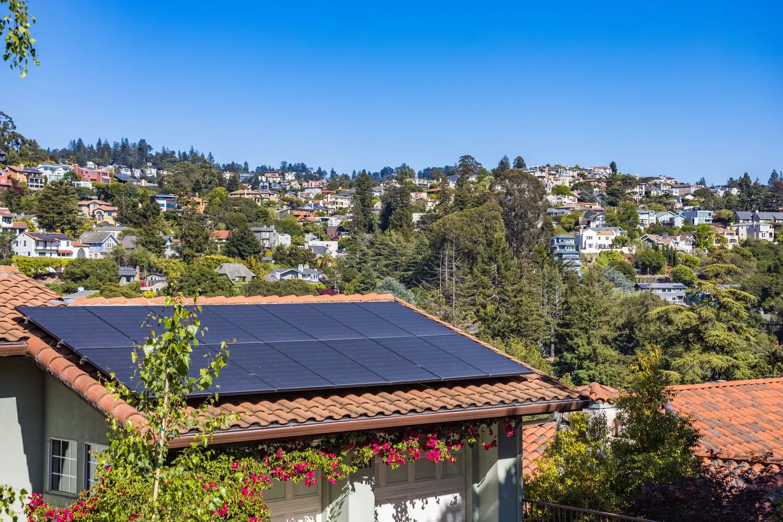 Casa na encosta com painéis solares no telhado e a cidade ao fundo