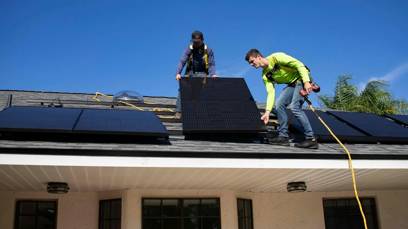 Dois instaladores posicionando painéis solares em um telhado