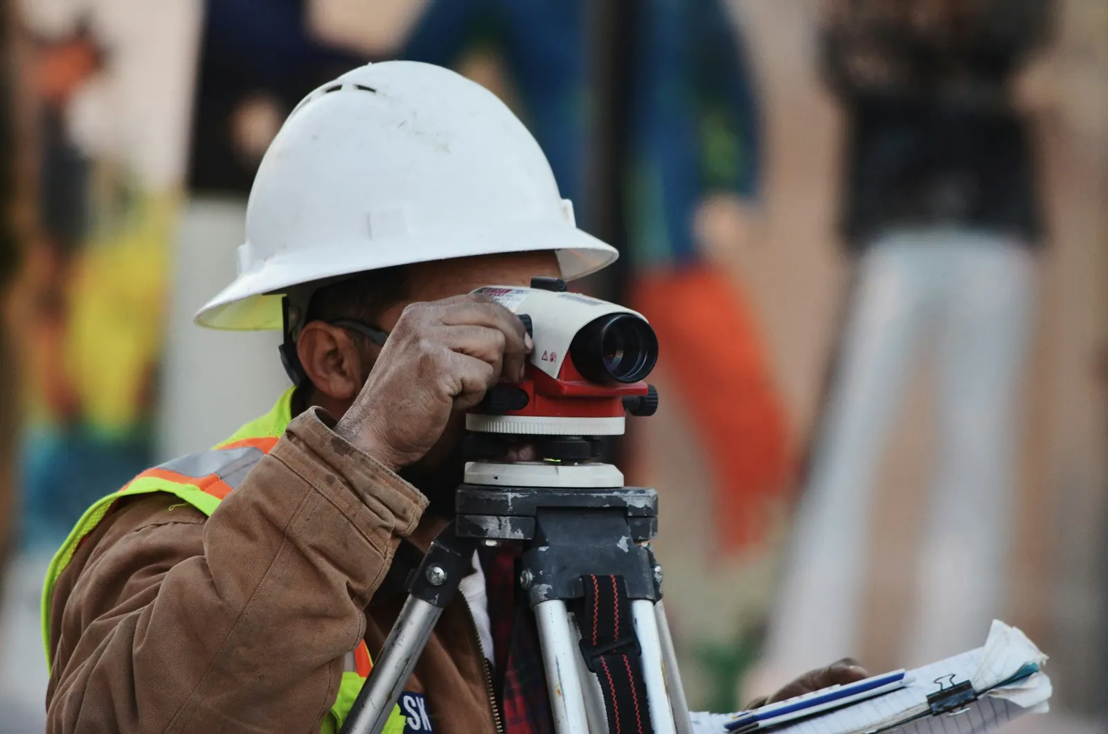 Topógrafo usando nível óptico no terreno da obra