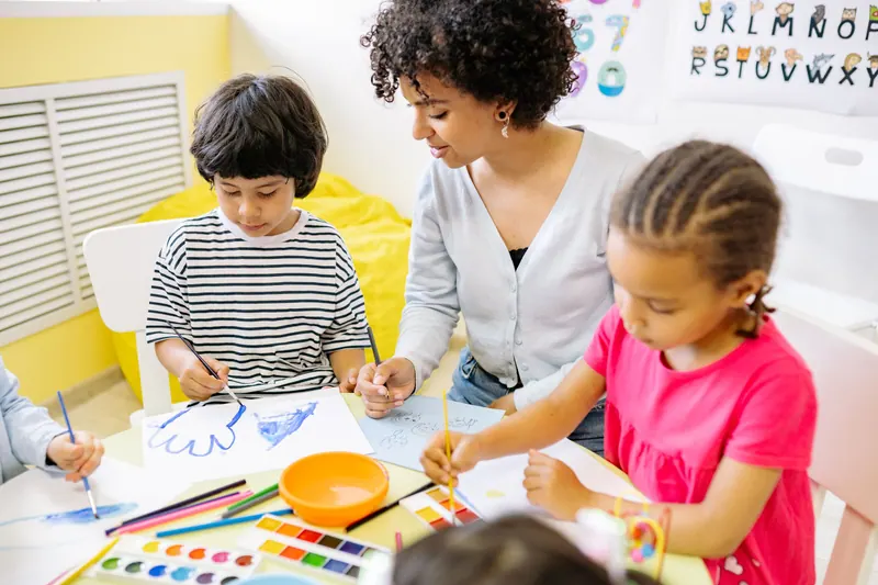 Crianças pintando aquarela com a professora