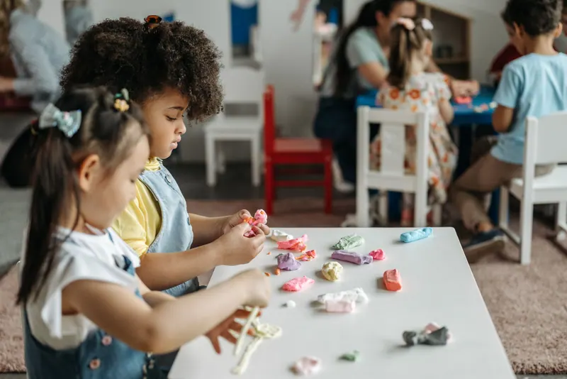 Meninas modelando massinha na mesa da sala