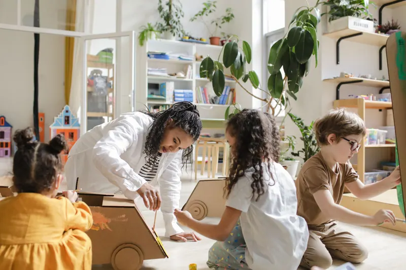 Crianças e professora montando um projeto com caixa de papelão