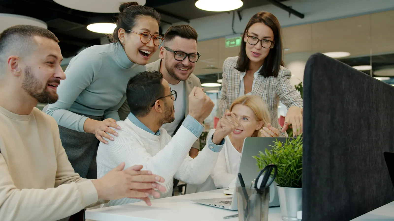 Equipe comemorando resultado em volta do computador