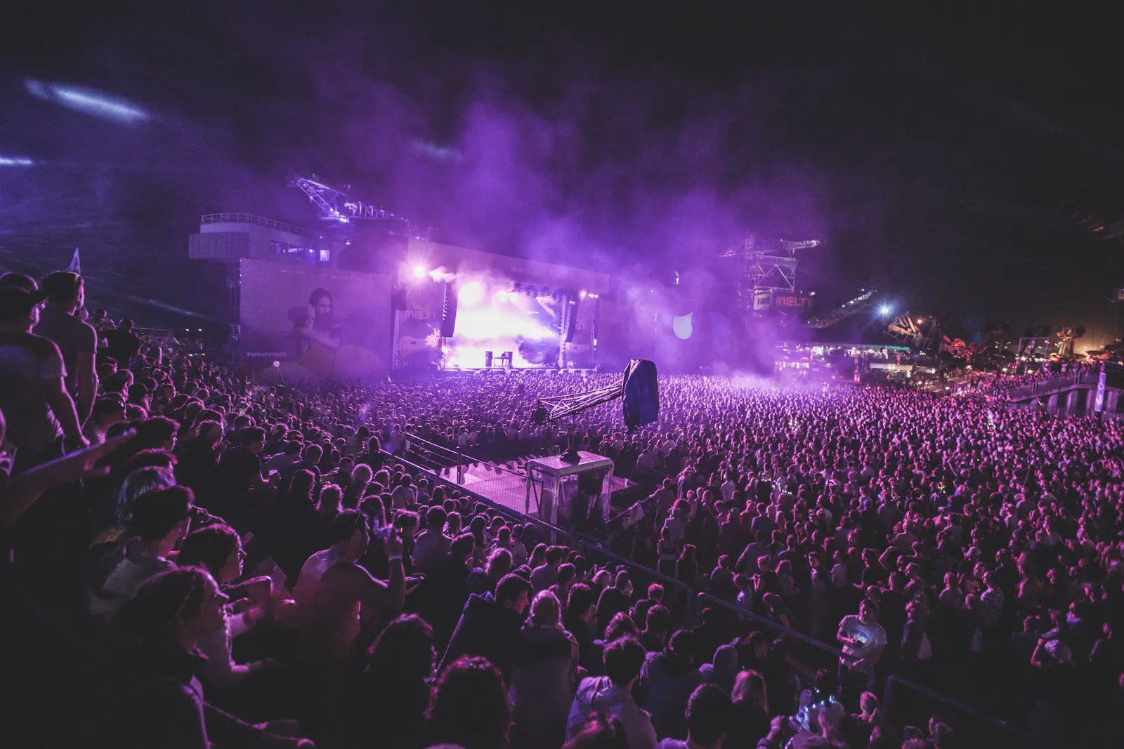 Arena lotada sob luz roxa durante o show