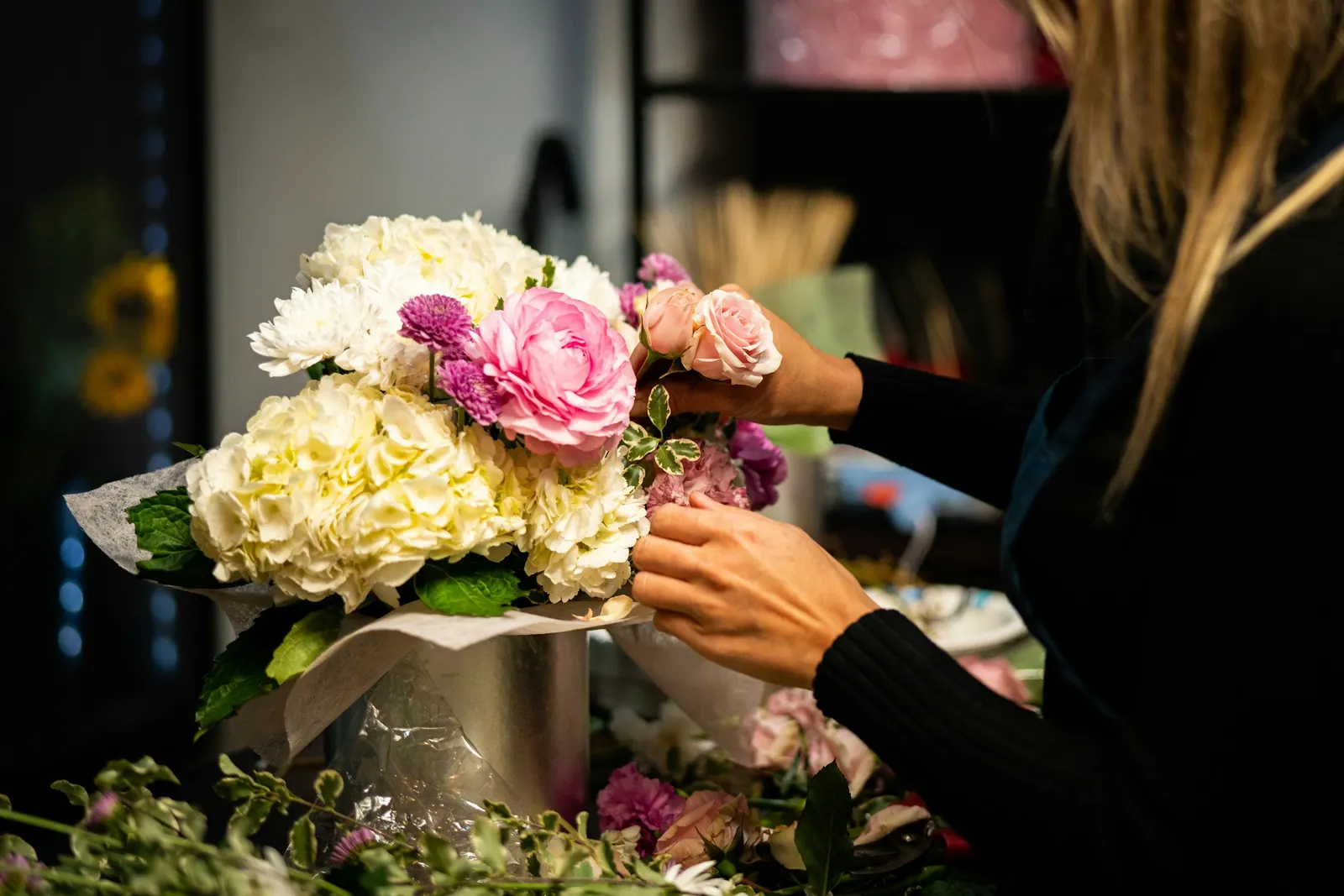 Florista montando um arranjo de flores claras
