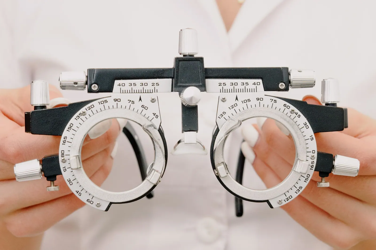 Mãos segurando a armação de prova usada na medição das lentes