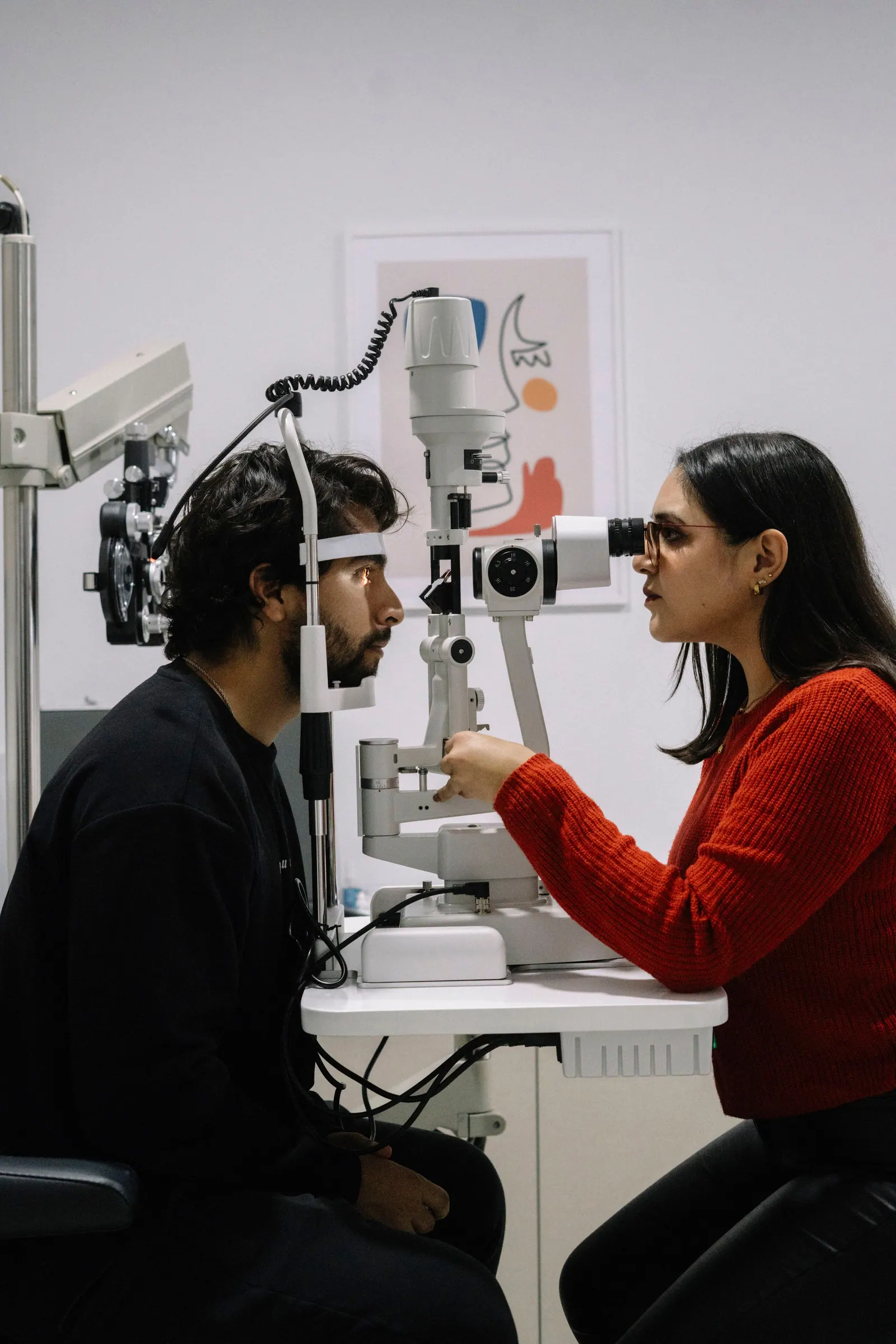 Exame com lâmpada de fenda, paciente e optometrista frente a frente