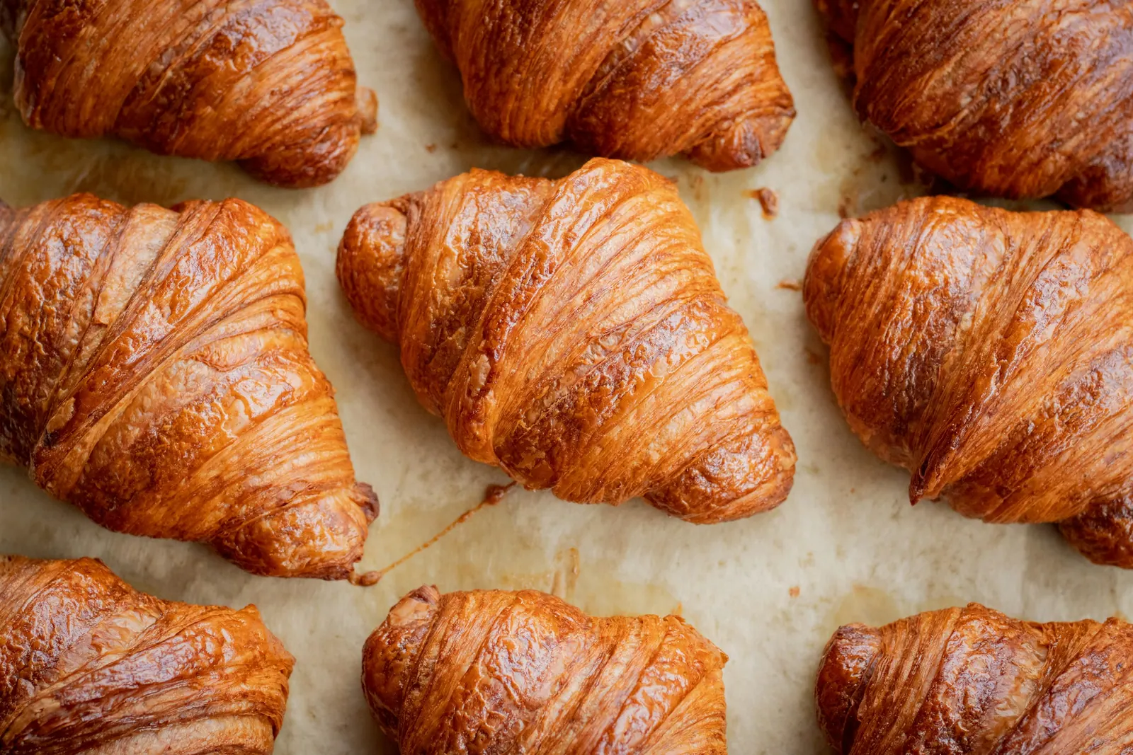 Croissants dourados vistos de cima sobre papel manteiga