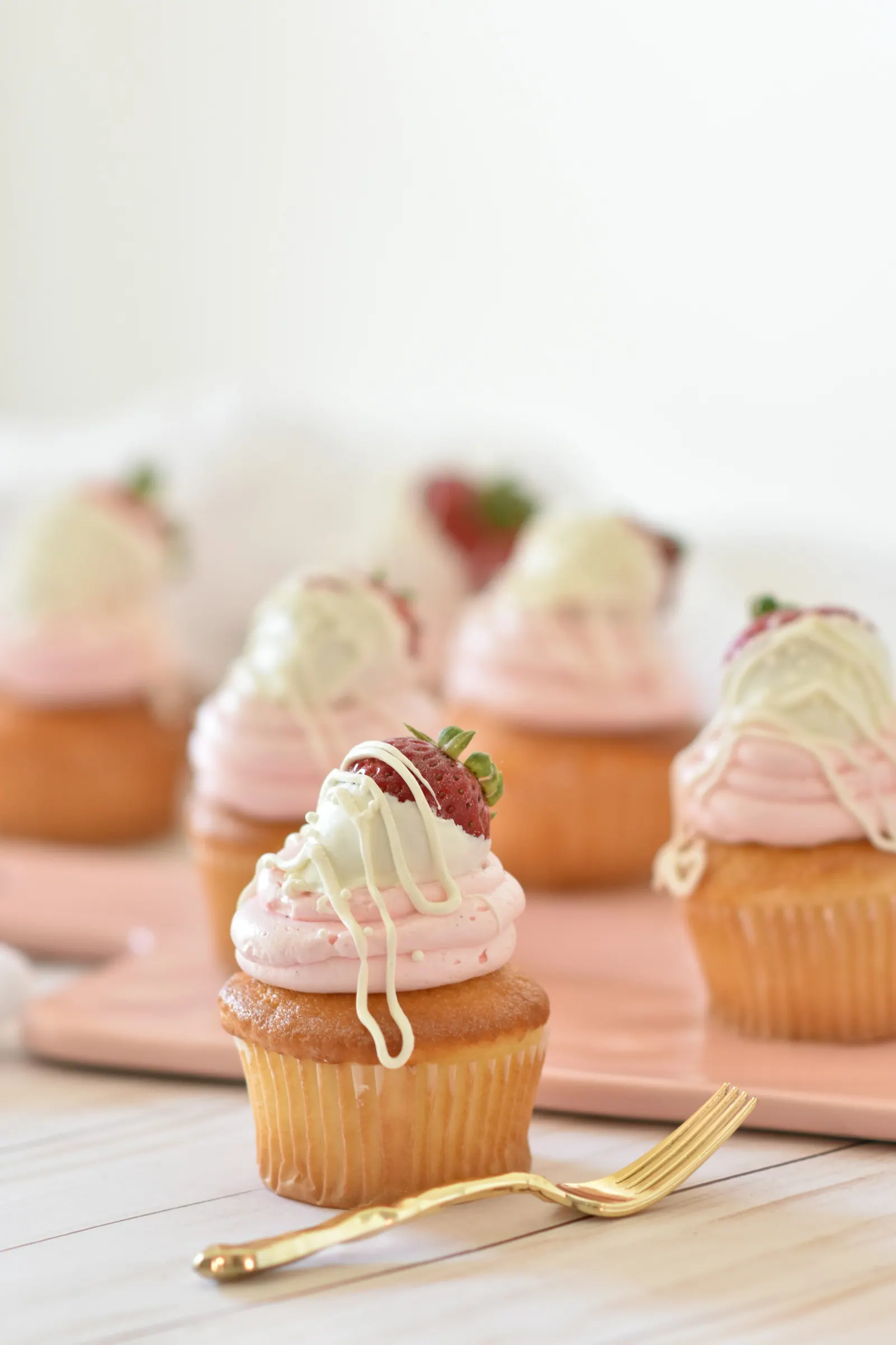 Cupcakes com cobertura e morango sobre bandeja rosa