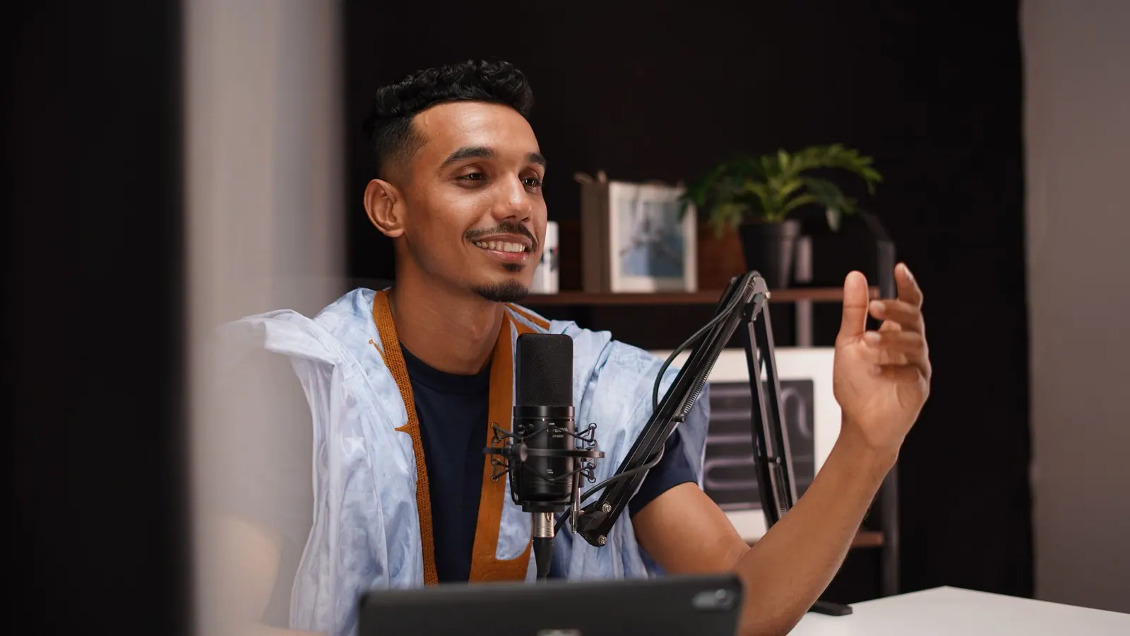 Apresentador sorrindo enquanto grava diante do microfone