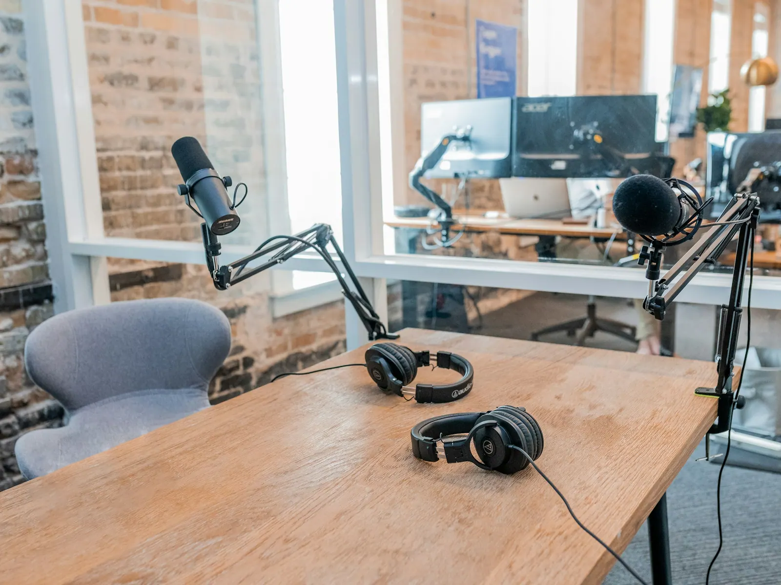 Mesa de podcast com microfones em braços articulados e fones