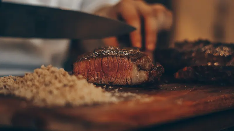 Faca cortando um bife sobre a tábua