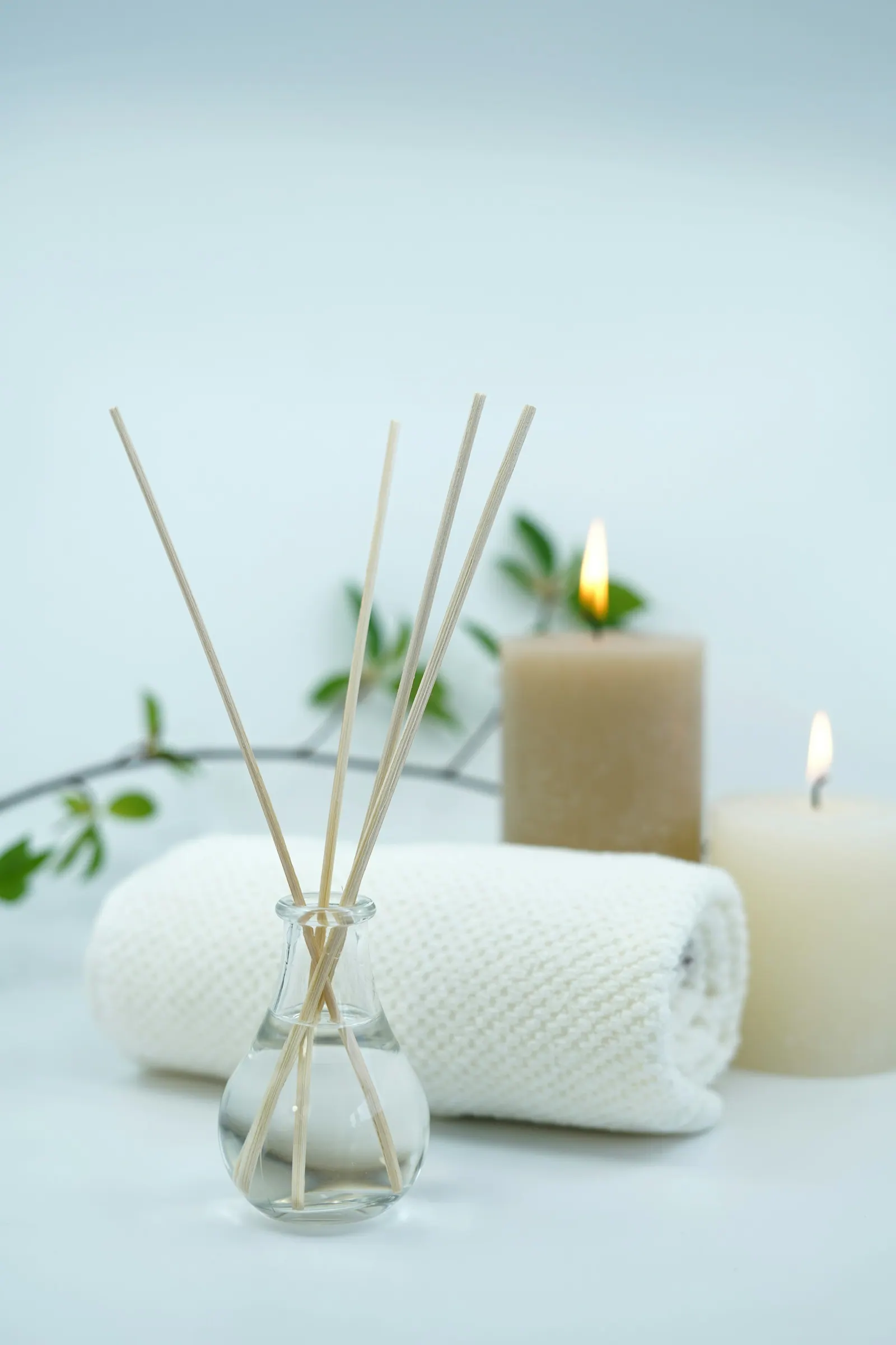 Aromatizador de varetas, velas e toalhas sobre fundo claro