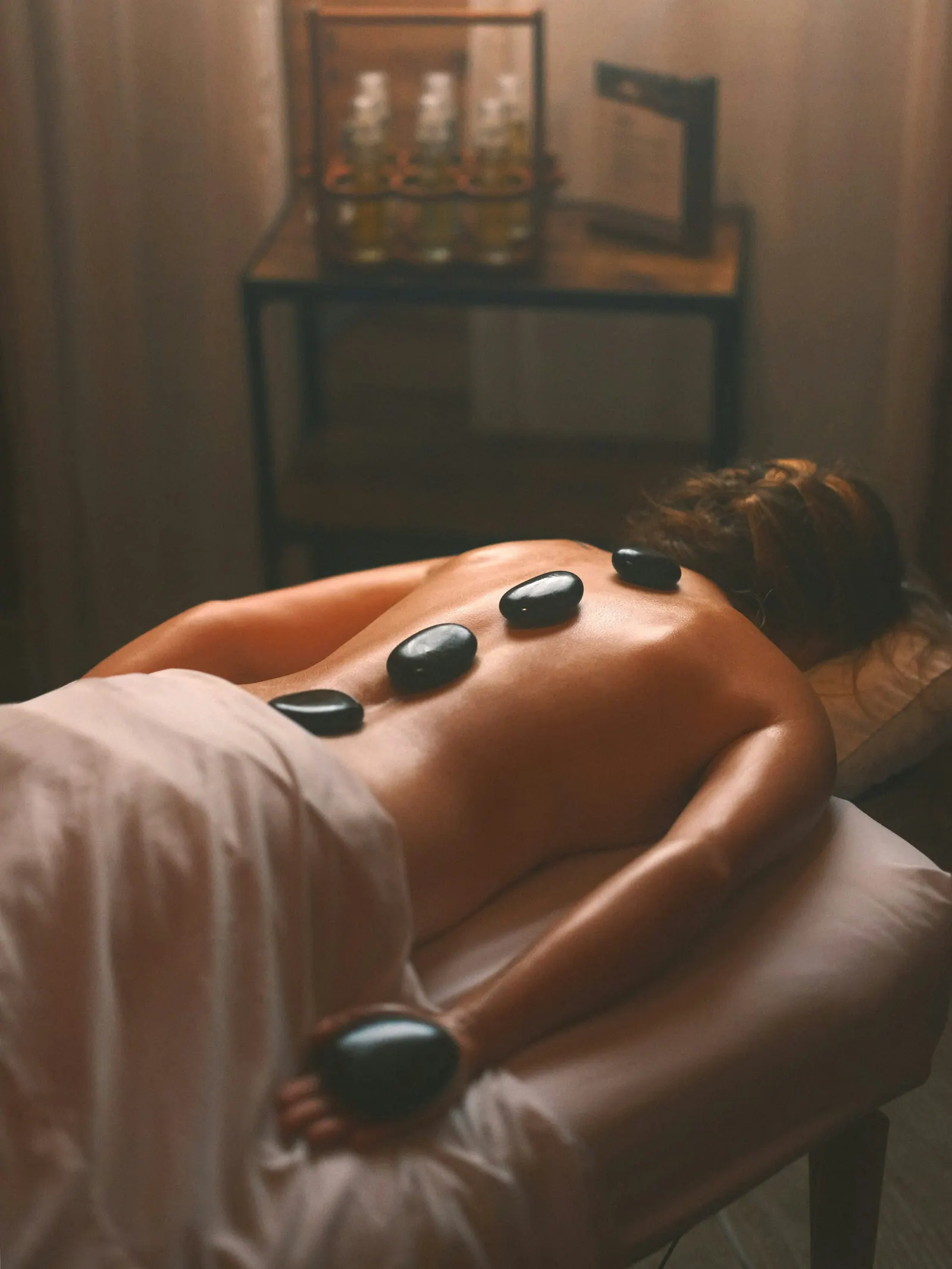Cliente relaxando com pedras quentes em sala de spa aconchegante