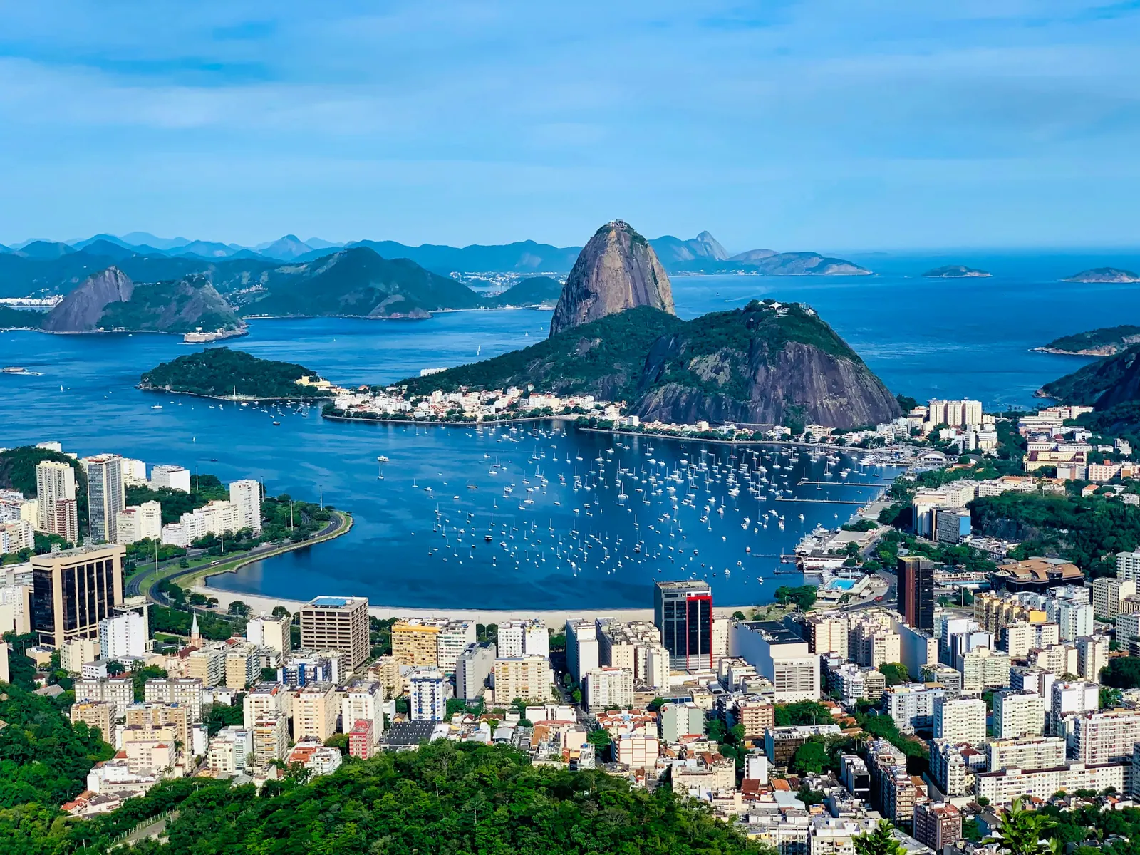 Enseada com barcos, prédios e Pão de Açúcar sob céu azul